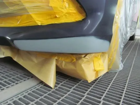 凹みのあるような深い傷ではなく、擦り傷程度でしたのでキズ周辺をサンディングで塗膜を削り落として、下地処理のサフェーサを塗布します。<br>サフェーサには防水・防錆の効果もあり塗料が長持ちします。<br>塗装をする前に塗料がかかってはマズイ部分をマスキングして塗料の飛散による汚れを防止します。