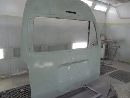 新品のバックドア及びバンパーは現車の色に合わせて塗装を行います。<br>これから塗装に入りますが、それぞれに単体で塗装を行います。<br>塗装は専用のブースで行いホコリ等の付着などを防止します。<br>塗装の前の下地処理として、サフェーサを塗布します。<br>その後に塗装面を細かいサンドペーパーで傷をつける足付けの作業をすることにより塗装の食いつきを良くします。