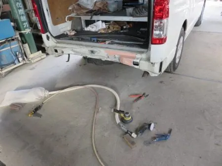 バックパネル(床)の凹みは、修正機で専用の冶具を使い引き出して修正をします。<br>修正箇所をサンディングで周囲の塗膜を削り落としてその跡にパテを盛り付けて平滑に仕上げていきます。<br>パテが乾燥したら下地処理のサフェーサを塗布して塗装に備えます。