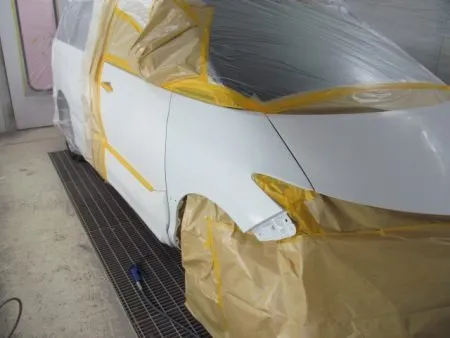 今回はフェンダーの交換で塗装を実施しますが、隣り合うフロントドア及びボンネットのぼかし塗装も含めて行います。<br>まずは、車を塗装専用ブースに移動して、塗料の飛散による汚れを防止するためのマスキングを行います。 <br>その後に下地処理として、塗装面を細かいサンドペパーで傷つける足付けの作業を行います。<br>次に、脂分・ワックス分を専用の溶剤で落とす脱脂の作業をします。