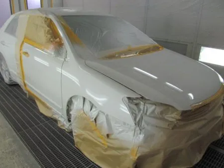 今回の塗装はフェンダーに隣接するボンネット及びピラー、フロントドアのぼかし塗装も含めて行う事になります。<br>まず、塗装色を現車の色に合わせて作っていきますが、調色は専門の塗装職人が数種類のサンプルを作成して、最も現車の色に近い色をベースカラーとして決定します。<br>ベースカラーが決定すると塗料を専用のスプレーガンで数回に分けて吹き付けていきます。<br>その次に透明なクリア塗装をします。<br>クリアのベースと硬化剤を混ぜて塗装します。<br>トップコートとしてのクリア塗装をすることで、塗料の紫外線による塗料の劣化防止及び対候性を高めることが出来ます。