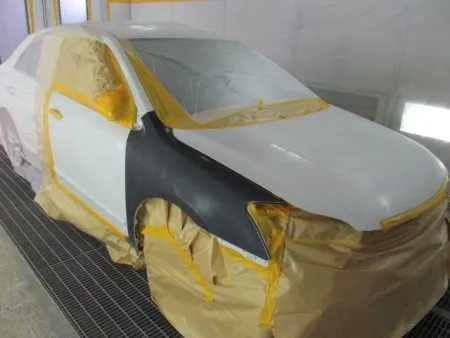 新しいフェンダーが入庫して、建付けを確認しながら取り付けて行きました。<br>新品のフェンダーは非常に高い防錆力を持つ電着塗装が施された状態で供給されます。<br>(殆どの場合黒い塗装膜)なので、現車の色に合わせて塗装をすることとなります。<br>塗装は専用のブース(密閉した部屋)にて塗装中のホコリの付着などを防ぎます。<br>さらに塗装中の塗料の飛散による汚れを防止するために、塗装面以外は全て専用のビニールシートやペーパーでマスキングを行ってから塗装を開始します。<br>マスキングは隙間の無いように厳重にしないと隙間から塗料が入って汚してしまうので、意外とシビアな作業になります。<br>次の工程として塗装面の脂分・ワックス分を専用の溶剤で落とす脱脂の作業を行います。