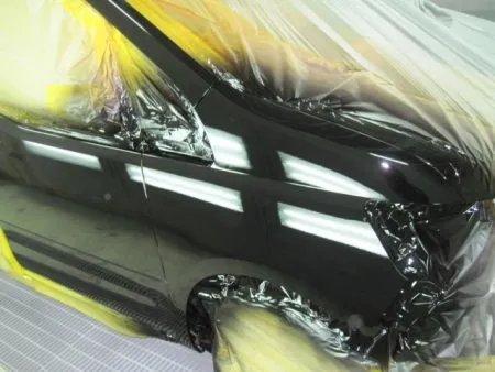 新しいフェンダーが入庫して、建付けを確認しながら取り付けて行きました。<br>新品のフェンダーは非常に高い防錆力を持つ電着塗装が施された状態で供給されます。<br>(殆どの場合黒い塗装膜)なので、現車の色に合わせて塗装をすることとなります。<br>塗装は専用のブース(密閉した部屋)にて塗装中のホコリの付着などを防ぎます。<br>さらに塗装中の塗料の飛散による汚れを防止するために、塗装面以外は全て専用のビニールシートやペーパーでマスキングを行ってから塗装を開始します。<br>マスキングは隙間の無いように厳重にしないと隙間から塗料が入って汚してしまうので、意外とシビアな作業になります。<br>次の工程として塗装面の脂分・ワックス分を専用の溶剤で落とす脱脂の作業を行います。<br>今回の塗装はフェンダーに隣接するピラー及びフロントドアのぼかし塗装も含めて行う事になります。<br>まず、塗装色を現車の色に合わせて作っていきますが、調色は専門の塗装職人が数種類のサンプルを作成して、車に直あてして、最も現車の色に近い色をベースカラーとして決めます。<br>ベースカラーが決定すると塗料を専用のスプレーガンで数回に分けて吹き付けていきます。<br>その次に透明なクリア塗装をします。<br>クリアのベースと硬化剤を混ぜて塗装します。<br>トップコートとしてのクリア塗装をすることで、紫外線による塗料の劣化防止及び対候性を高めることが出来ます。