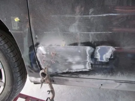 フロントドア下部の凹み部分は内側から叩き出して修正することが出来ないので、スタッドと呼ばれるピンを複数スタッド溶接して専用の治具を取り付け引き出して修正します。