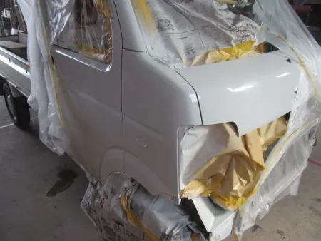 これから塗装工程に入ります。<br>塗装は専用のブース(密閉した部屋)にて塗装中のホコリの付着などを防ぎます。<br>さらに塗装中の塗料の飛散による汚れを防止するために、塗装面以外は全て専用のビニールシートやペーパーでマスキングを行ってから塗装を開始します。<br>次の工程として塗装面の脂分・ワックス分を専用の溶剤で落とす脱脂の作業を行います。<br>今回の塗装はフェンダーに隣接するピラー及びフロントドア、ボンネットフードのぼかし塗装も含めて行う事になります。<br>バンパーは別に単体で塗装を行います。<br>まず、塗装色を現車の色に合わせて作っていますが、調色は専門の塗装職人が数種類のサンプルを作成して、最も現車の色に近い色をベースカラーとして決めます。<br>ベースカラーが決定すると塗料を専用のスプレーガンで数回に分けて吹き付けていきます。<br>その次に透明なクリア塗装をします。<br>クリアのベースと硬化剤を混ぜて塗装します。<br>トップコートとしてのクリア塗装をすることで、紫外線による塗料の劣化防止及び対候性を高めることが出来ます。