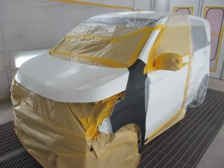 新しいフェンダーが入庫して、建付けを確認しながら取り付けて行きました。<br>新品のドア写真のように非常に高い防錆力を持つ黒い塗装膜の電着塗装が施された状態で供給されます。<br>なので、現車の色に合わせて塗装をすることとなります。<br>塗装は専用のブース(密閉した部屋)にて塗装中のホコリの付着などを防ぎます。<br>さらに塗装中の塗料の飛散による汚れを防止するために、塗装面以外は全て専用のビニールシートやペーパーでマスキングを行ってから塗装を開始します。<br>マスキングはどこからか必ず漏れて車内に色がついてしまうので簡単そうに見えて結構シビアな作業になります。<br>塗装前の準備として、細かいサンドペーパー研磨する足付けを行います。<br>次に塗装面の脂分・ワックス分を専用の溶剤で落とす脱脂の作業を行います。<br>今回の塗装はフェンダーに隣接するボンネット及びフロントドア、ピラーのぼかし塗装も含めて行う事になります。<br>まず、塗装色を現車の色に合わせて作っていきますが、調色は専門の塗装職人が数種類のサンプルを作成して、車に直あてして、最も現車の色に近い色をベースカラーとして決めます。<br>ベースカラーが決定すると塗料を専用のスプレーガンで数回に分けて吹き付けていきます。