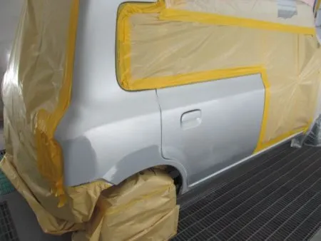 サフェーサーも乾いたら表面をサンドペーパーで磨き、滑らかにします。<br>塗装ブースへ移動して塗装に取り掛かります。<br>塗装前に、塗装面の掃除(脱脂作業)を行い、目に見えない脂汚れなどをしっかりと落とします。<br>これをすることによって塗装の食いつきがよくなり、塗装が長持ちします。<br>塗料が掛かってはいけない所をマスキングして、塗装に入ります。